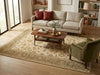 Load image into Gallery viewer, A styled living room featuring a large beige and green traditional patterned area rug under a wooden coffee table, with a cream sofa, an olive green armchair, and bookshelves in the background.