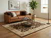 Load image into Gallery viewer, A styled living room scene featuring a brown leather sofa, a large patterned area rug, a round coffee table, a floor lamp, and a potted plant in a bright room with wood floors and a window.