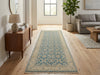 Load image into Gallery viewer, A long runner rug with a blue and beige traditional floral pattern is displayed on a light wood floor in a bright, modern living room.