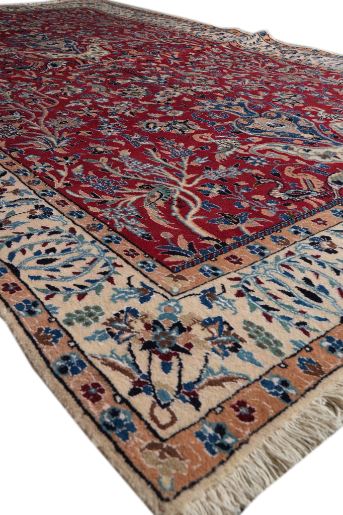 A traditional oriental area rug with a deep red field, beige border, and blue floral motifs, shown on a white background.