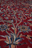 Load image into Gallery viewer, A close-up of a traditional patterned rug with a deep red background and intricate floral motifs in blue, beige, and black.