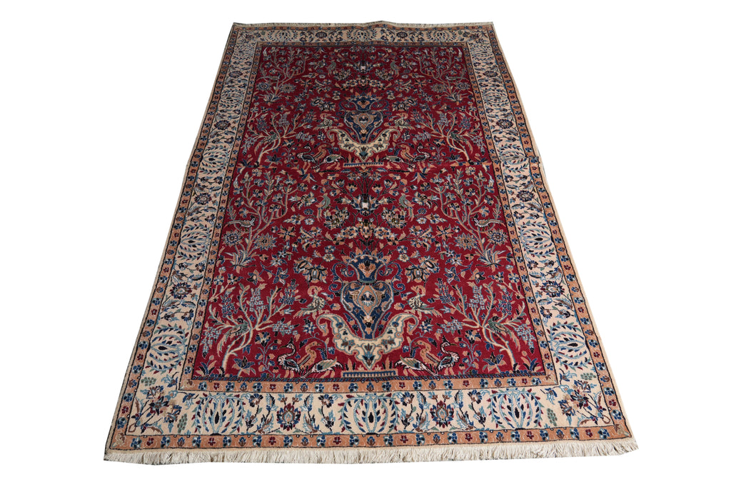 A traditional oriental area rug with a deep red field, intricate floral motifs, and a detailed cream and blue border, shown flat against a white background.