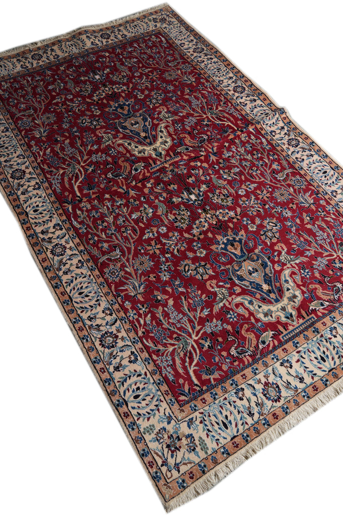 A traditional oriental area rug with a deep red field, beige and blue borders, and floral motifs, shown on a plain white background.
