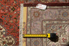 Load image into Gallery viewer, A close-up overhead view of a patterned area rug with a tape measure laid across the center and a small white tag reading 7x10ft on the upper edge, showing the rug's color and scale.