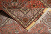 Load image into Gallery viewer, A close-up of a patterned area rug with a folded corner showing its cream and rust borders, featuring a central floral medallion and multicolored motifs.