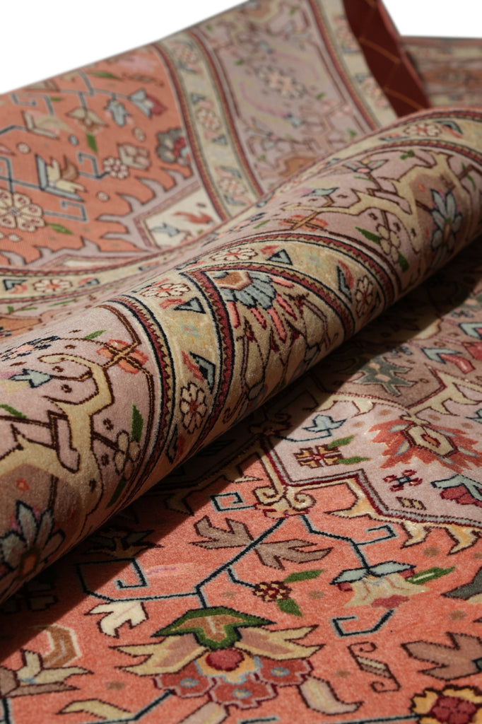 A close-up of a rolled area rug showing its intricate traditional pattern in warm tones of terracotta, beige, and brown.