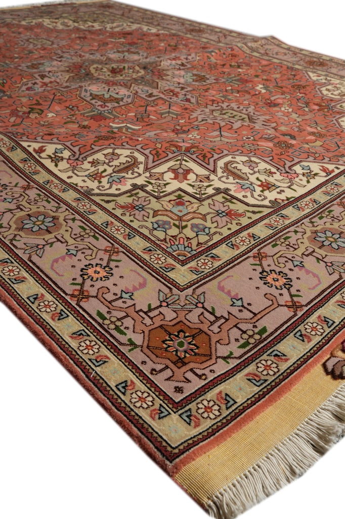 A traditional Persian-style area rug with a warm rust red field, beige border, and intricate floral motifs in blue, green, and pink, shown on a white background.