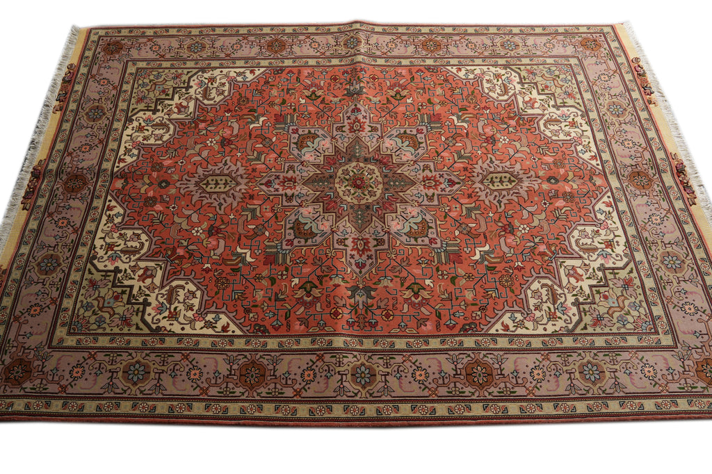 A traditional Persian-style area rug with a complex geometric and floral pattern, featuring a dominant red central field, beige and brown borders, and small blue accents.
