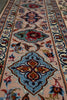 Load image into Gallery viewer, A close-up view of a traditional patterned area rug with a beige base, featuring a large blue medallion with red and orange floral details, surrounded by smaller floral motifs and a decorative border.