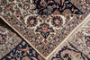 Load image into Gallery viewer, A close-up of an ornate Persian-style area rug with cream, navy, red, and gold floral motifs and fringed edges.