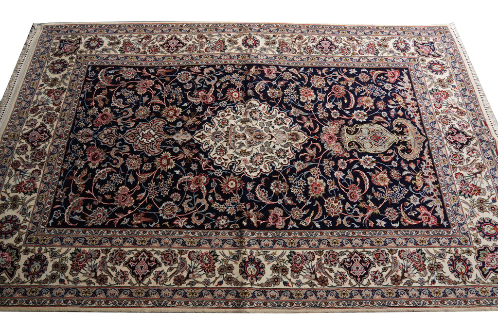 A traditional oriental area rug with a dark navy blue central field, intricate floral motifs in beige, red, and blue, and a wide cream-colored border.