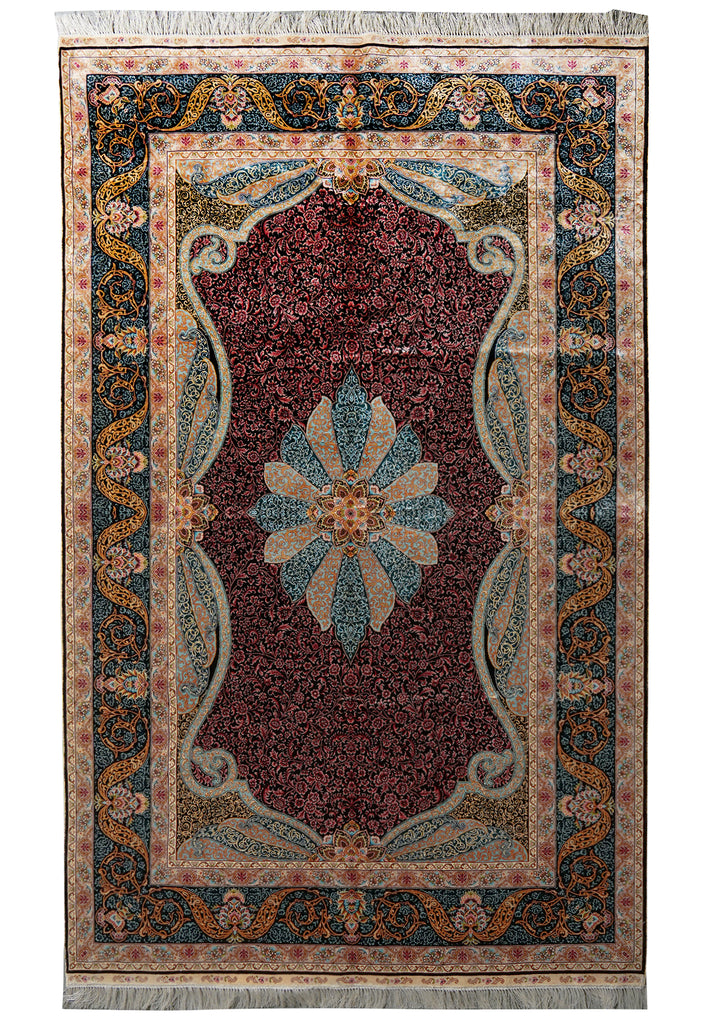 A traditional rectangular area rug with a deep burgundy central field, a large blue and beige floral medallion, and an ornate navy, beige, and gold patterned border with fringe on the top and bottom.