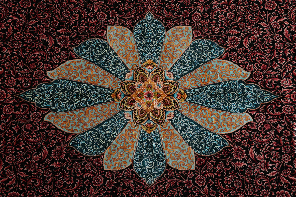 An ornate Persian-style textile or rug pattern featuring a large central floral medallion with teal and gold patterned petals on a dark red and black floral background.