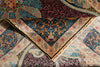 Load image into Gallery viewer, A close-up of an ornate patterned rug with folded sections showing its intricate design, fringed edge, and rich color palette of navy, burgundy, gold, and beige.