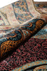 Load image into Gallery viewer, A close-up of a folded patterned rug showing intricate traditional motifs in black, burgundy, teal, gold, and beige.