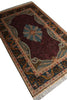 Load image into Gallery viewer, A rectangular traditional area rug with a dark red central field, a large floral medallion in muted blue and beige, and an ornate border in navy, gold, and cream, shown on a white background.