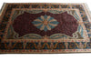 Load image into Gallery viewer, A traditional oriental area rug with a dark red central field, a blue and beige floral medallion, and an ornate patterned border in blue, beige, and gold.