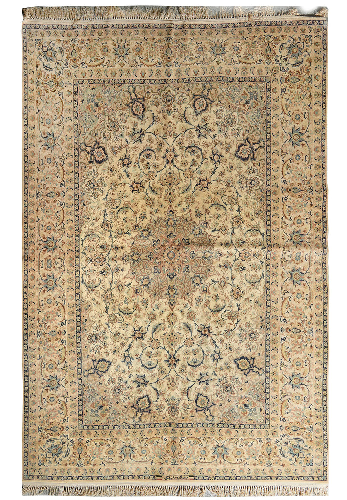An antique Persian-style area rug with a beige and cream base, decorated with intricate floral motifs in muted blue, brown, and rust red, featuring a central medallion and fringed edges.