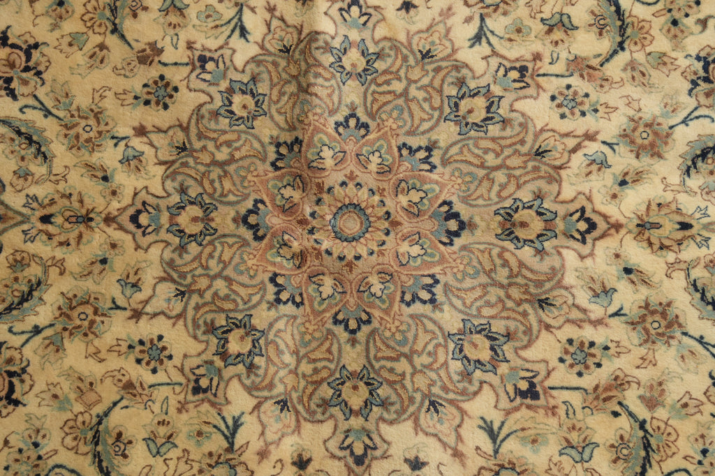 A close-up of an ornate patterned rug with a central medallion design in beige, brown, blue, and muted green tones.