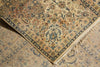 Load image into Gallery viewer, A close-up of an ornate area rug with a beige base and intricate floral motifs in blue, green, and rust tones, showing the corner and fringed edge.