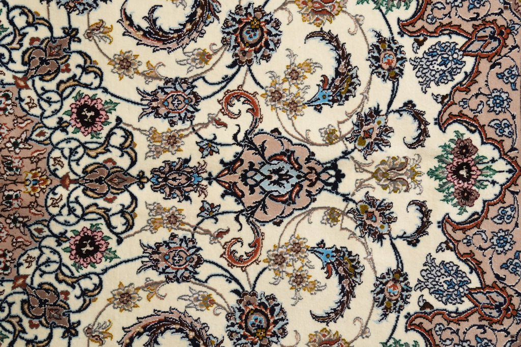 A close-up of an ornate traditional patterned rug with a cream background and intricate floral motifs in brown, blue, green, and pink.
