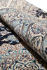 Load image into Gallery viewer, A close-up of a rolled area rug showing an intricate traditional pattern in beige, blue, brown, and navy tones.
