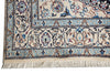 Load image into Gallery viewer, Close-up of a traditional patterned rug corner showing cream, blue, navy, and rust floral motifs with fringe along the bottom edge.