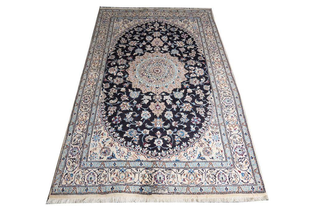 A traditional oriental area rug with a central medallion, featuring a dark navy blue field, beige and cream borders, and light blue floral details, shown flat against a white background.