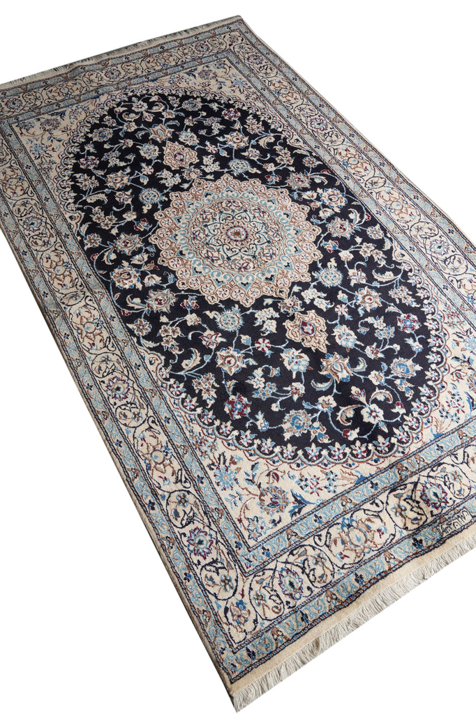 A rectangular Persian-style area rug with a central medallion and intricate floral motifs, shown from an elevated angle on a white background.