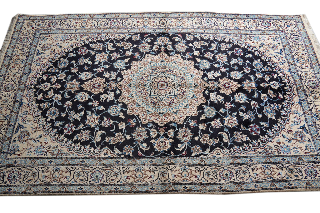 A traditional oriental area rug with a dark navy blue central field, featuring a large oval medallion and intricate floral motifs in beige, light blue, and cream, surrounded by a patterned border.