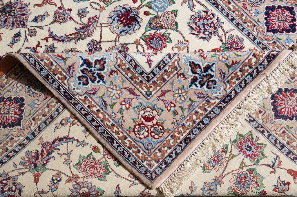 A close-up of a traditional patterned rug with cream, beige, and red floral motifs, featuring a detailed geometric border and fringed edges.
