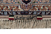 Load image into Gallery viewer, Close-up of a patterned rug with beige, brown, blue, and red woven floral motifs, a fringed bottom edge, and a small woven label with Persian text and green, white, and red side bands.
