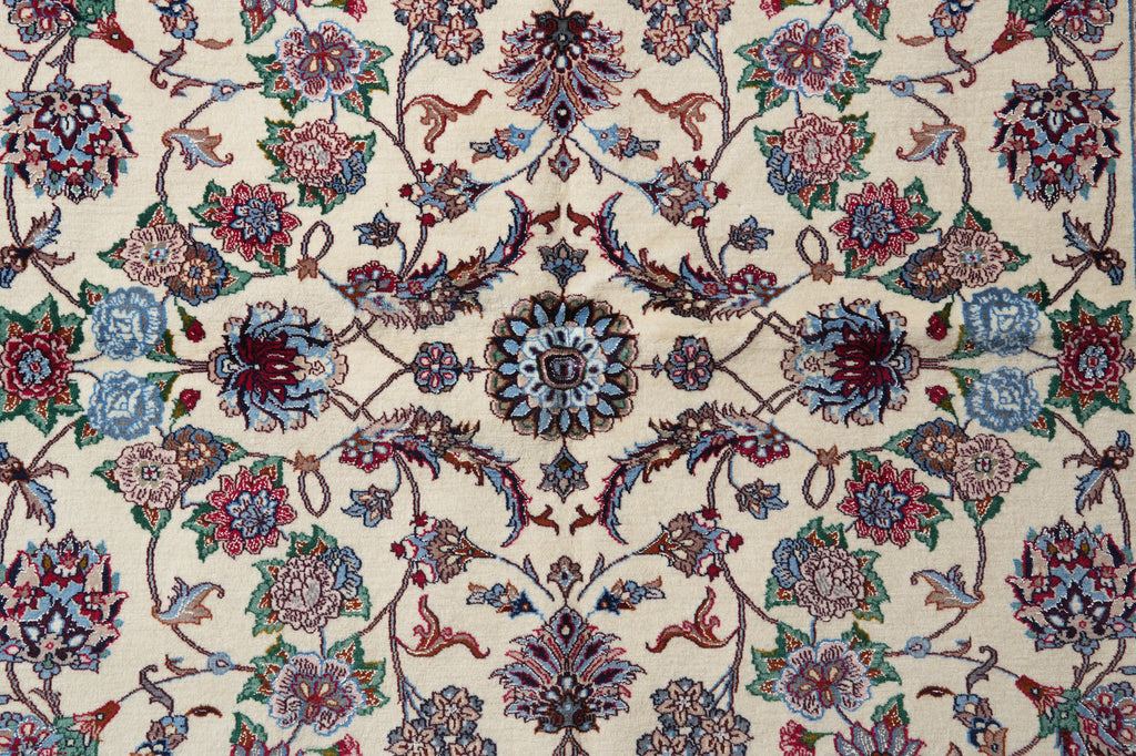 A close-up of an ornate floral patterned rug with a cream background and intricate motifs in blue, red, green, and brown.