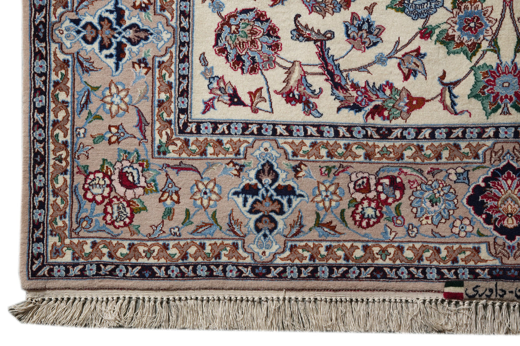 Close-up of an ornate traditional rug corner showing a cream field, floral motifs in blue, red, and green, a beige border, and fringe along the bottom edge.