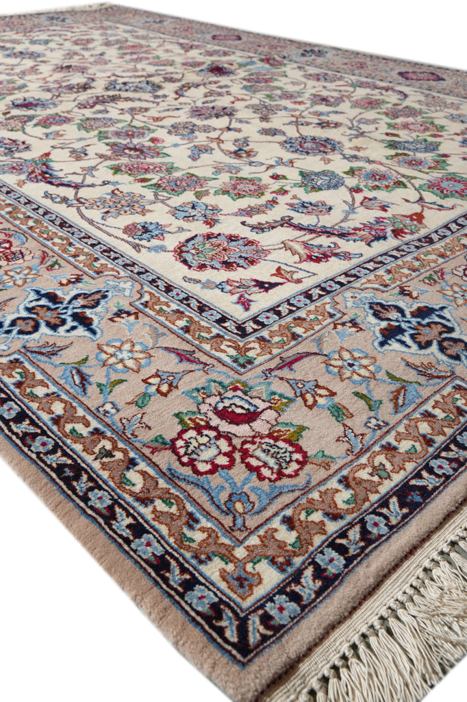 A traditional Persian-style area rug with an intricate floral pattern, featuring a cream center field, beige borders, and multicolored details including blue, red, and green, finished with a fringed edge.