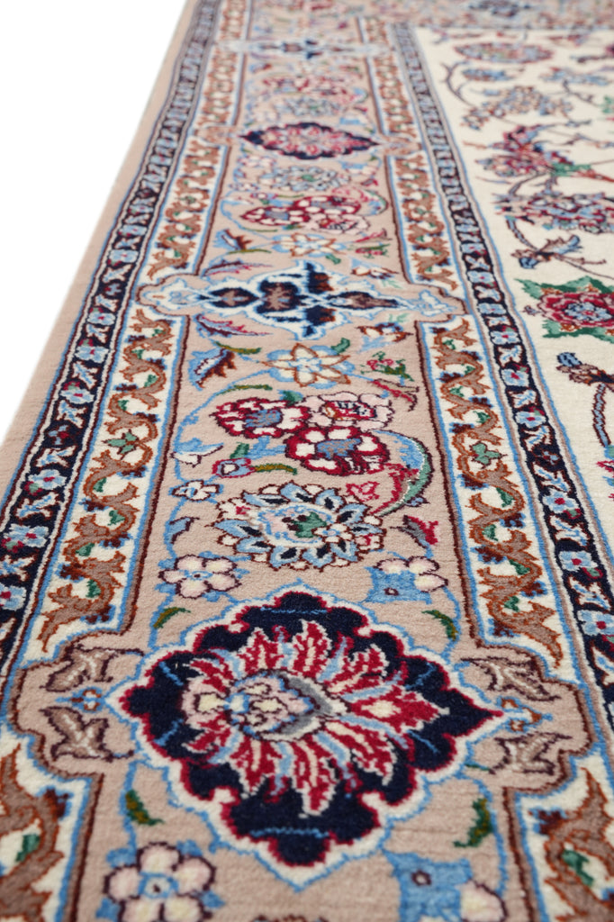 A close-up, angled view of a traditional oriental area rug with a beige base, featuring intricate floral motifs in red, blue, green, and brown, bordered by detailed patterns.