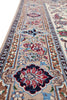 Load image into Gallery viewer, A close-up, angled view of a traditional oriental area rug with a beige base, featuring intricate floral motifs in red, blue, green, and brown, bordered by detailed patterns.