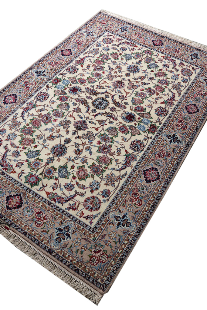 A rectangular traditional area rug with an intricate floral and vine pattern, featuring a cream center, detailed blue, red, and green motifs, and a beige border with fringe on the ends.