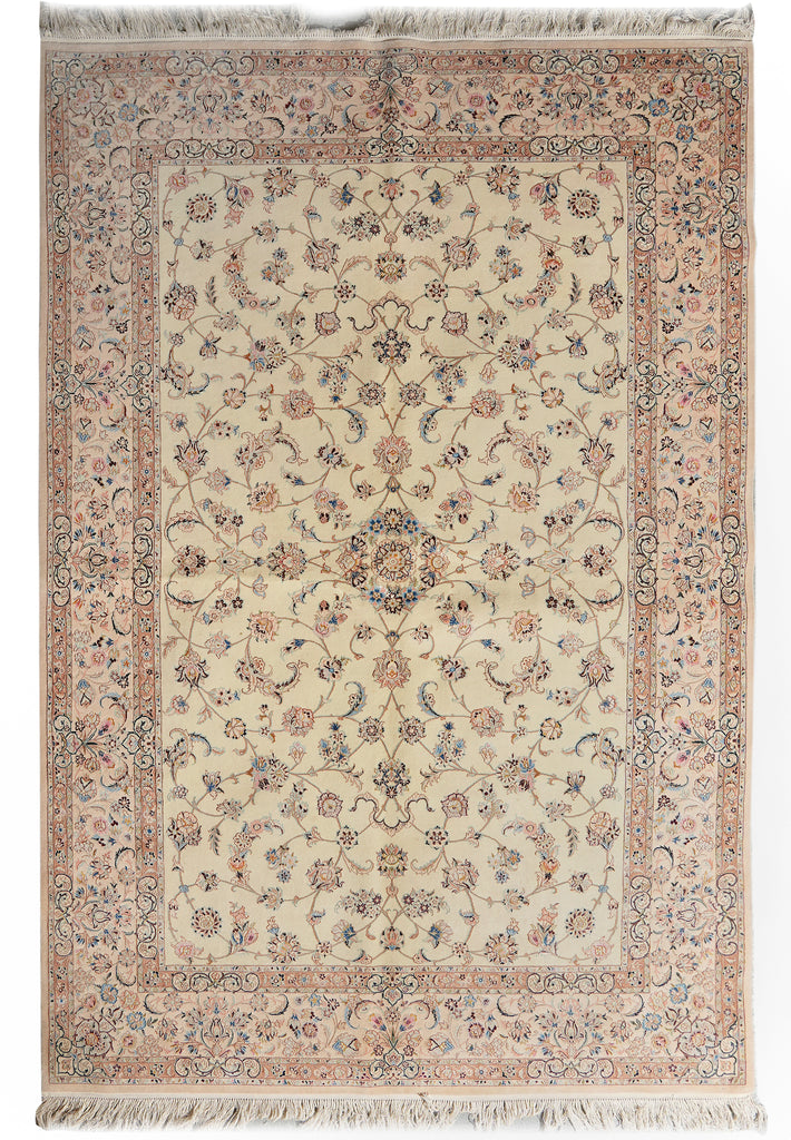A traditional rectangular area rug with an intricate floral and vine pattern, featuring a cream center field, a dusty pink border, and fringed edges on all four sides.