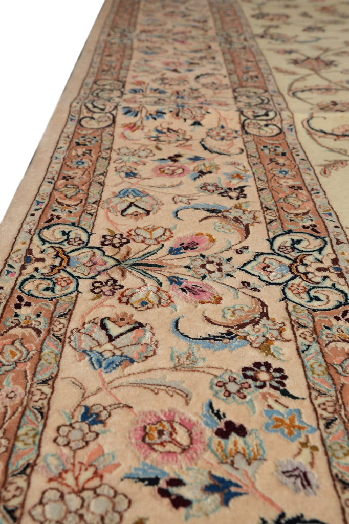 A close-up view of a traditional oriental rug with a beige background and an intricate floral pattern in shades of blue, pink, brown, and green.