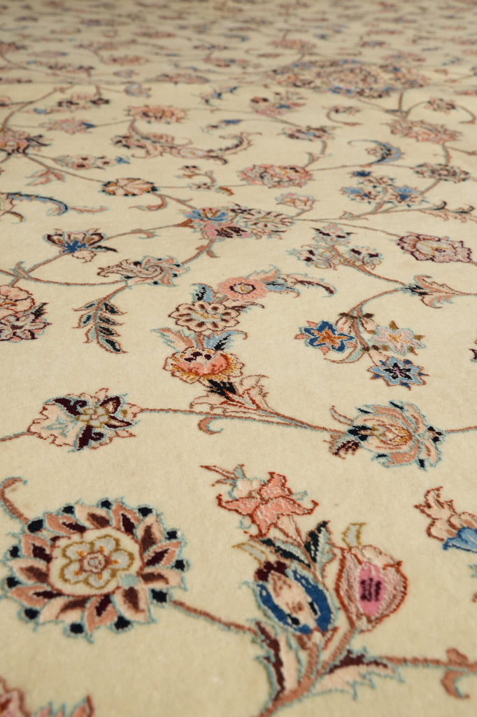Close-up of a traditional patterned rug with a cream background and delicate floral motifs in pink, blue, and brown.