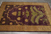 Load image into Gallery viewer, A rectangular area rug with a deep burgundy center field featuring a large green botanical motif and gold thistle-like floral elements, surrounded by a wide gold and beige patterned border, laid flat on a gray tiled floor.