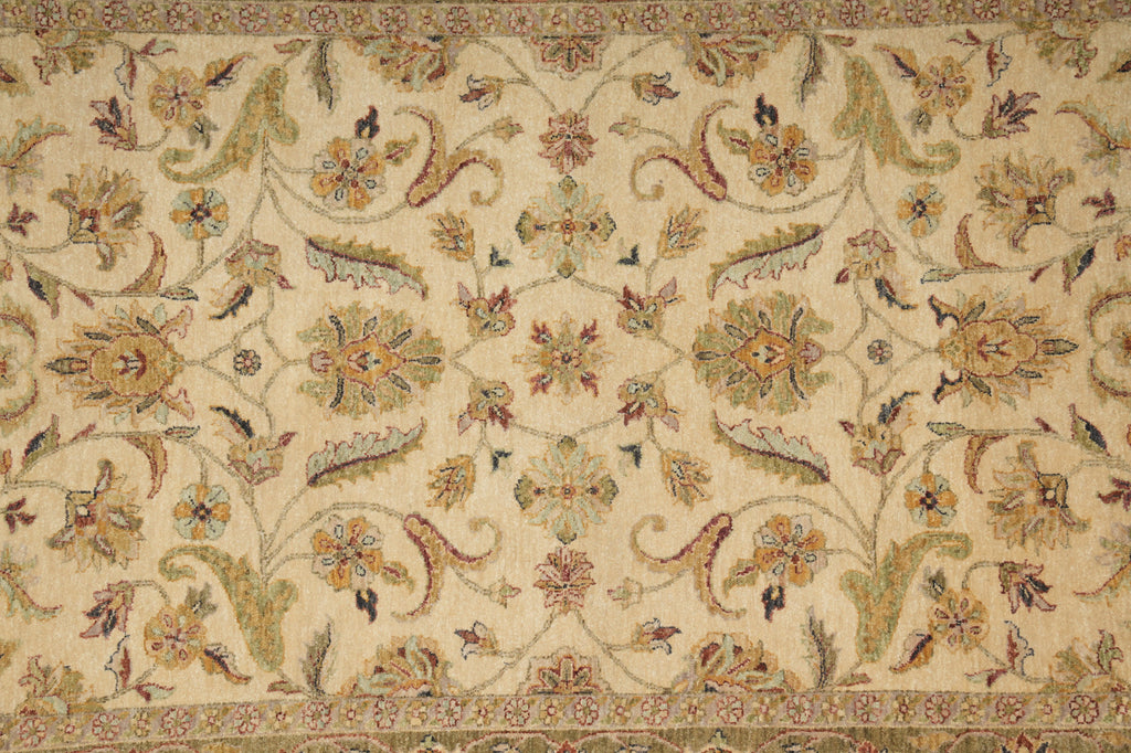 An ornate vintage-style area rug with a cream background and a detailed floral and scroll pattern in muted green, gold, and terracotta tones.
