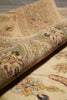 Load image into Gallery viewer, A close-up of a rolled area rug showing its detailed traditional floral and paisley pattern in beige, olive green, rust red, and dark accents.