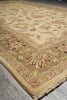 Load image into Gallery viewer, A close-up view of a traditional oriental area rug with a cream and olive green base, featuring floral motifs and a patterned border, laid out on a gray concrete floor.