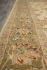 Load image into Gallery viewer, A close-up view of a traditional patterned area rug with a sage green base, featuring floral motifs in beige, rust red, and dark blue, laid out on a gray floor.