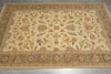 Load image into Gallery viewer, A rectangular area rug with an intricate traditional floral and paisley pattern, featuring a beige center field and a wide olive-green border, laid out on a gray tiled floor.