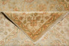 Load image into Gallery viewer, A close-up of a folded area rug showing its intricate floral pattern in beige, muted green, and dusty orange tones, with a fringed edge visible.