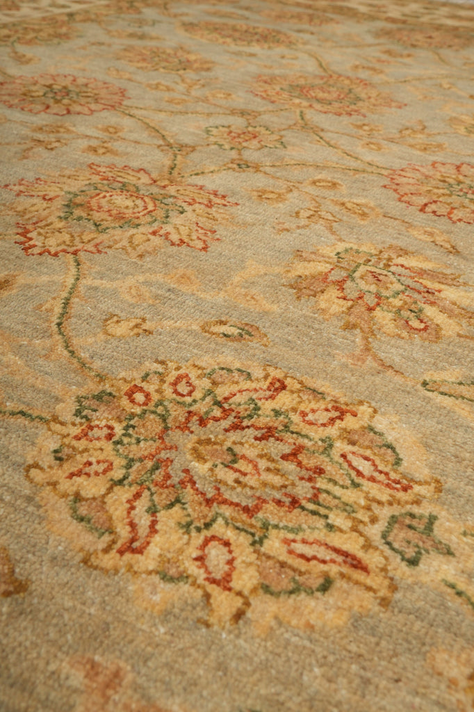 Close-up of a traditional patterned area rug with a beige base and floral motifs in muted red, green, and tan.