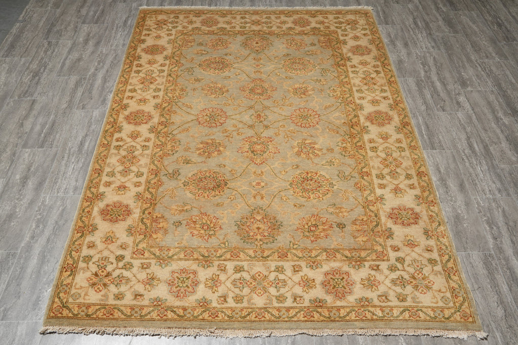 A rectangular area rug with an intricate traditional floral pattern, displayed flat on a gray wood-look floor.
